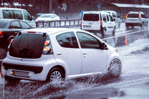 Ukraine. Kiev - 05,12,2019 Spraying water from the wheels of a vehicle moving on a wet city asphalt road. The wet wheel of a car moves at a speed along a puddle on a flooded city road during rain.
