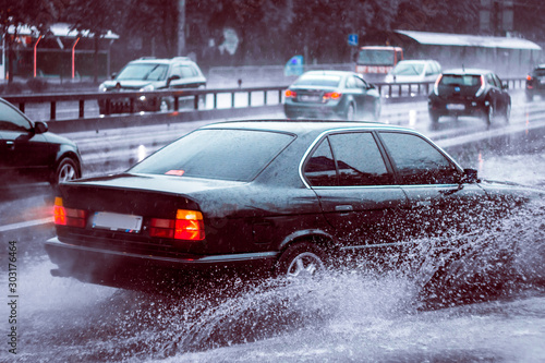 Ukraine. Kiev - 05,12,2019 Spraying water from the wheels of a vehicle moving on a wet city asphalt road. The wet wheel of a car moves at a speed along a puddle on a flooded city road during rain.