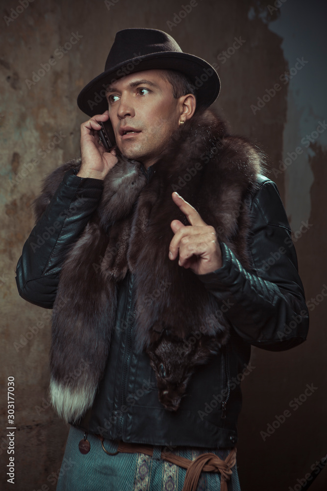 a man in a hat and leather jacket with a Fox collar talking to someone on the phone a man in a hat and leather jacket with a Fox collar talking to someone on the phone