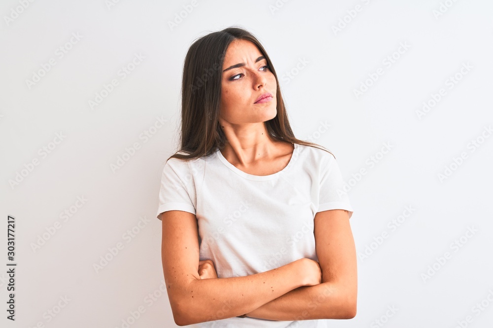 Young beautiful woman wearing casual t-shirt standing over isolated white background looking to the side with arms crossed convinced and confident Young beautiful woman wearing casual t-shirt standing over isolated white background looking to the side with arms crossed convinced and confident
