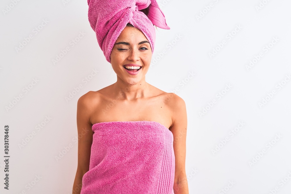 Young beautiful woman wearing shower towel after bath over isolated white background winking looking at the camera with sexy expression, cheerful and happy face. Young beautiful woman wearing shower towel after bath over isolated white background winking looking at the camera with sexy expression, cheerful and happy face.