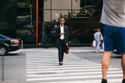 Attractive Businessman With A Mobile Phone Is Rushing To Work While Crossing The Road
