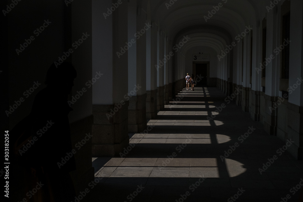  Tourists silhouettes walk through the bottom of a building with shadows and lights