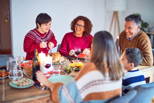 Beautiful family smiling happy and confident. One of them curving roasted turkey celebrating christmas at home