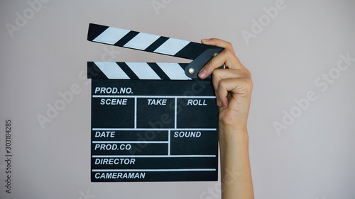 Fényképezés Female hands holding movie clapper isolated on gray background.