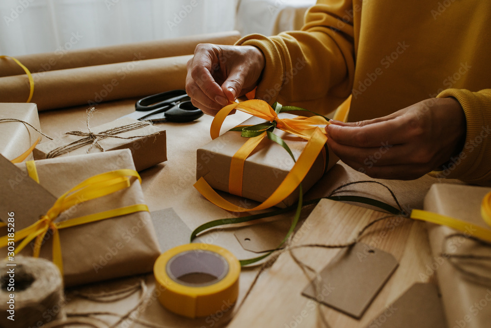 Obraz premium Woman packaging box. Kraft wrapping paper and natural twine. Recycling material. Happy holiday present, surprise. Gifts for boxing day. Delivery service, shipping. Handwork art craft. Celebration