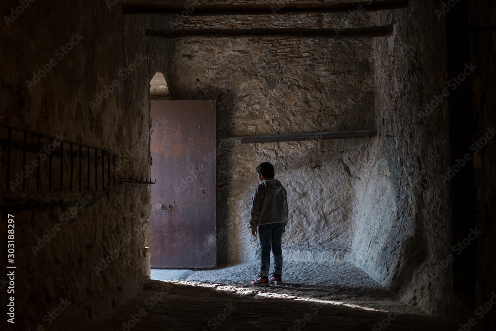  boy with his back facing the light coming out a door in the castle of xativa