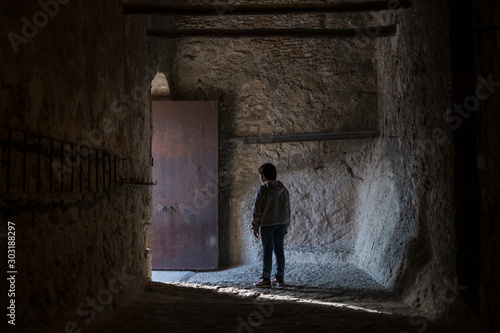  boy with his back facing the light coming out a door in the castle of xativa © Oscar