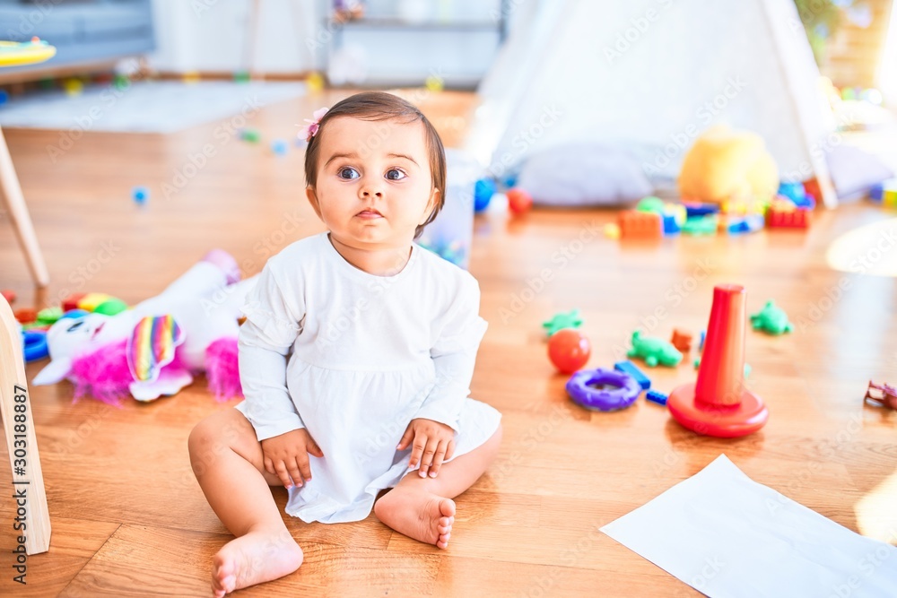 Beautiful infant happy at kindergarten around colorful toys