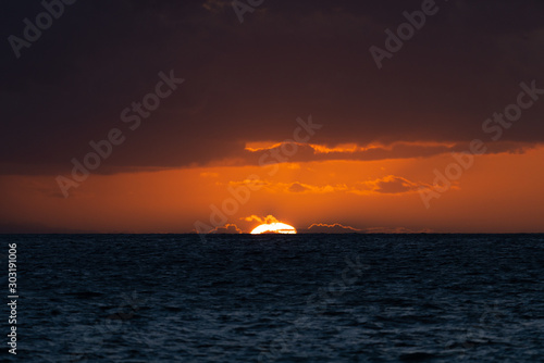 Beautiful sunset with sun touching the horizon of ocean in Hawaii