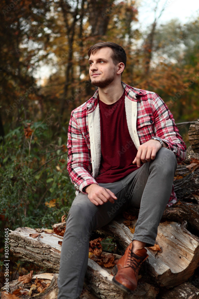 Young Man feet with brown leather boot, grey jeans, and red shirt in cage  .Siting on pile of firewood and looking Stock Photo | Adobe Stock
