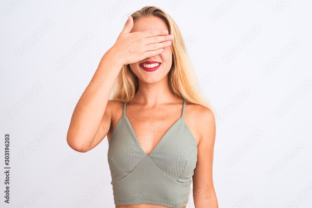 Young beautiful woman wearing casual green t-shirt standing over isolated white background smiling and laughing with hand on face covering eyes for surprise. Blind concept. Young beautiful woman wearing casual green t-shirt standing over isolated white background smiling and laughing with hand on face covering eyes for surprise. Blind concept.