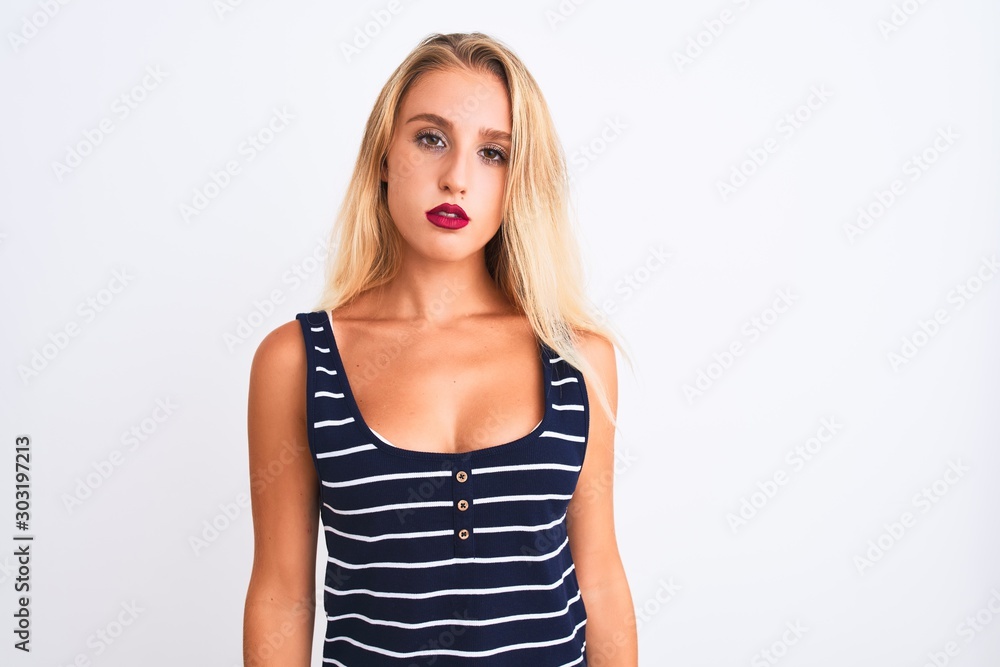 Young beautiful woman wearing casual striped t-shirt standing over isolated white background with serious expression on face. Simple and natural looking at the camera. Young beautiful woman wearing casual striped t-shirt standing over isolated white background with serious expression on face. Simple and natural looking at the camera.