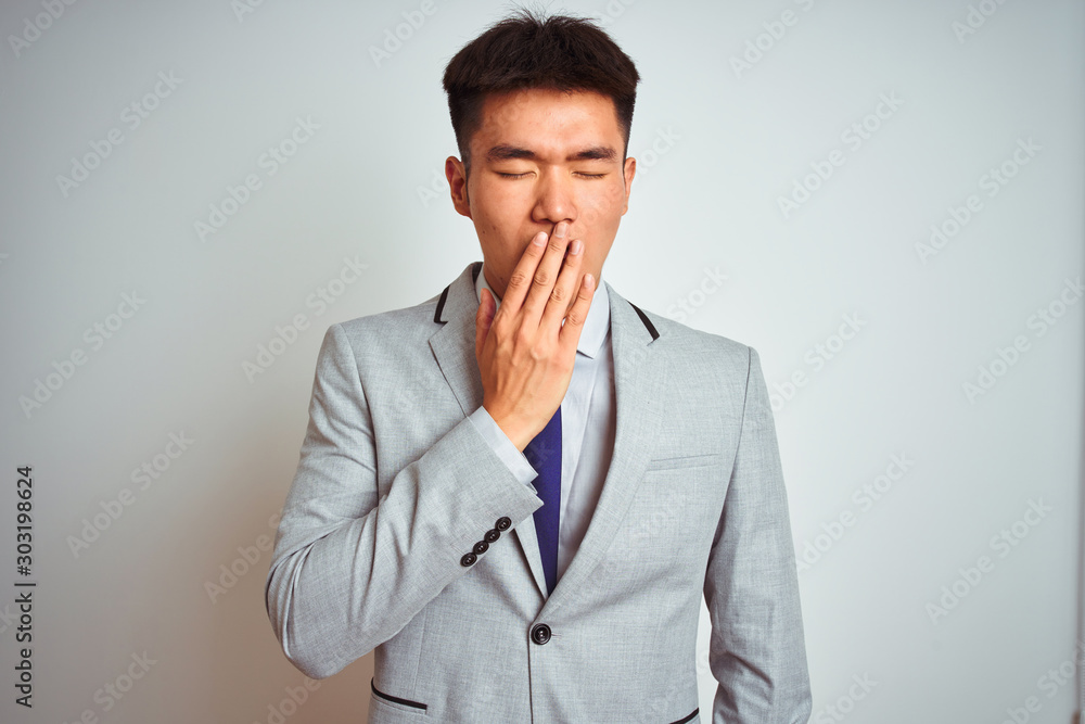 Asian chinese businessman wearing suit and tie standing over isolated yellow background bored yawning tired covering mouth with hand. Restless and sleepiness. Asian chinese businessman wearing suit and tie standing over isolated yellow background bored yawning tired covering mouth with hand. Restless and sleepiness.