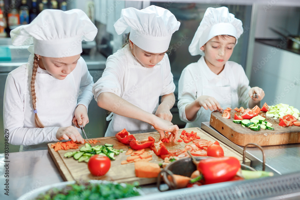 Children grind vegetables in the kitchen. Children grind vegetables in the kitchen.