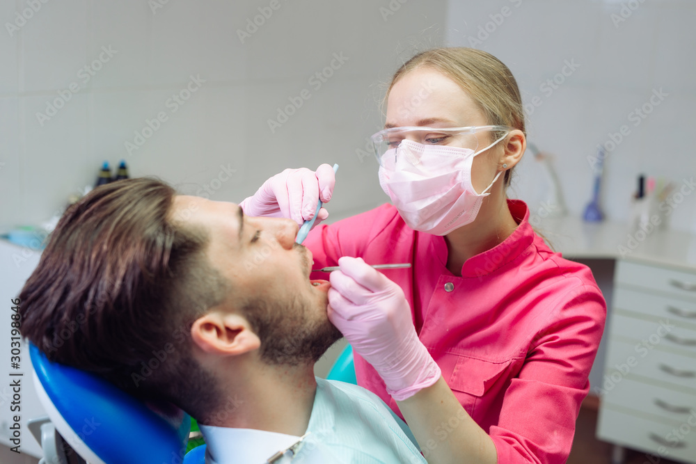 Professional teeth cleaning. Dentist cleans the teeth of a male patient.