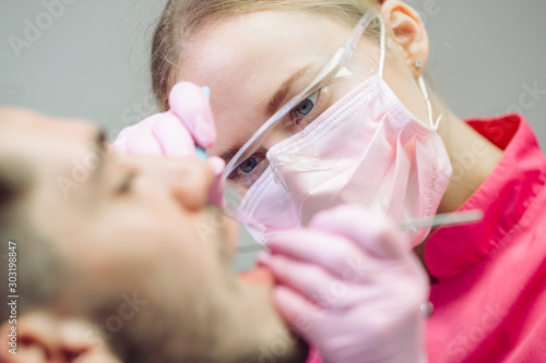 Professional teeth cleaning. Dentist cleans the teeth of a male patient.