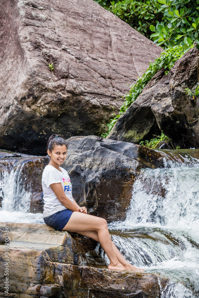 Young beautiful Srilankan girl sitting on a rock near a water stream Young beautiful Srilankan girl sitting on a rock near a water stream