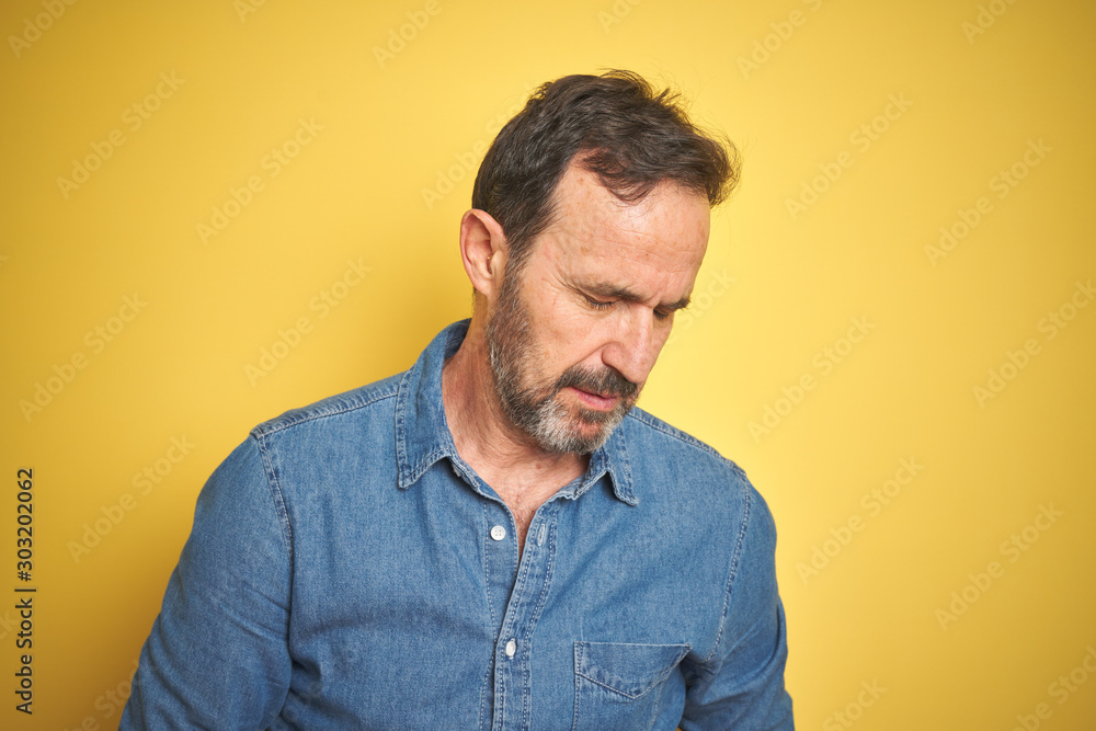 Handsome middle age senior man with grey hair over isolated yellow background with hand on stomach because indigestion, painful illness feeling unwell. Ache concept. Handsome middle age senior man with grey hair over isolated yellow background with hand on stomach because indigestion, painful illness feeling unwell. Ache concept.