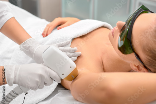Hair removal cosmetology procedure from a therapist at cosmetic beauty spa clinic. Laser epilation underarm. photo
