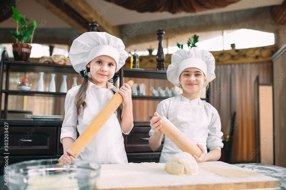 funny girls kids are preparing the dough in the kitchen. funny girls kids are preparing the dough in the kitchen.