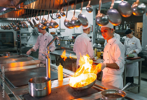 Modern kitchen. Cooks prepare meals on the stove in the kitchen of the restaurant or hotel. The fire in the kitchen. photo