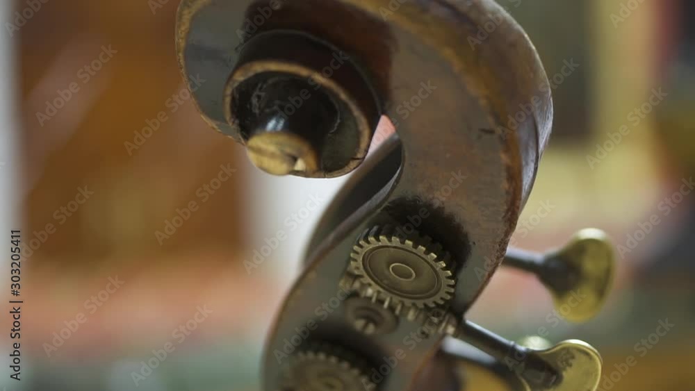 Closeup view of top of retro violin in modern interior of orchestra theater. Wooden part of vintage musical instrument in blur room. Concept: academic, traditional, artistic. Closeup view of top of retro violin in modern interior of orchestra theater. Wooden part of vintage musical instrument in blur room. Concept: academic, traditional, artistic.