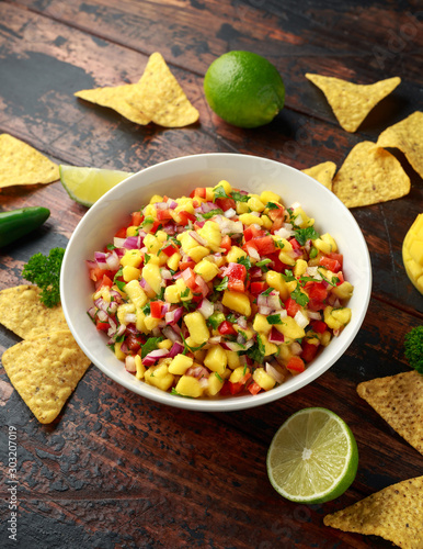 Bowl of fresh Mango Salsa with nachos chips and herbs. Healthy Vegan, Vegetables food.