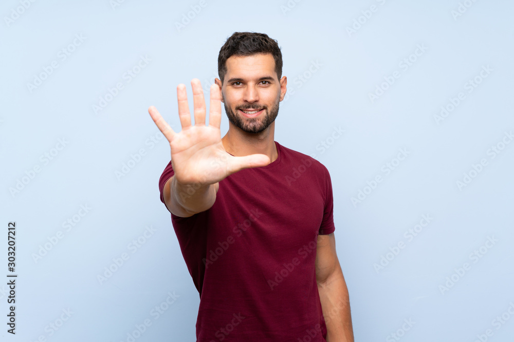 Fototapeta premium Handsome man over isolated blue background counting five with fingers