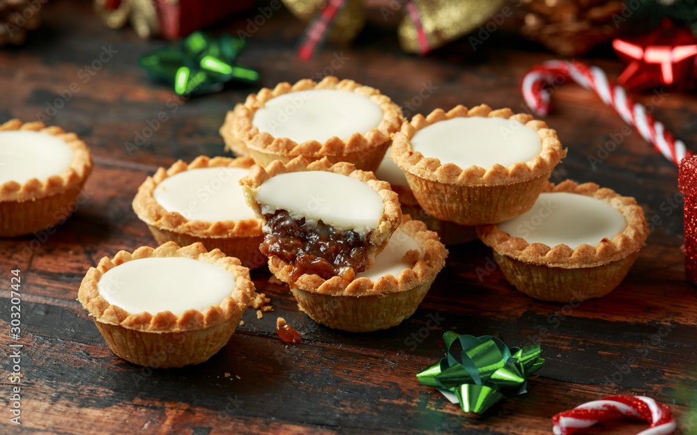British Christmas iced mince pies with decoration, gifts, green tree branch on wooden rustic table British Christmas iced mince pies with decoration, gifts, green tree branch on wooden rustic table