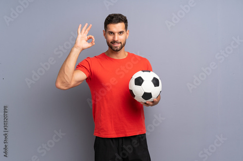 Handsome young football player man over isolated white wall showing ok sign with fingers