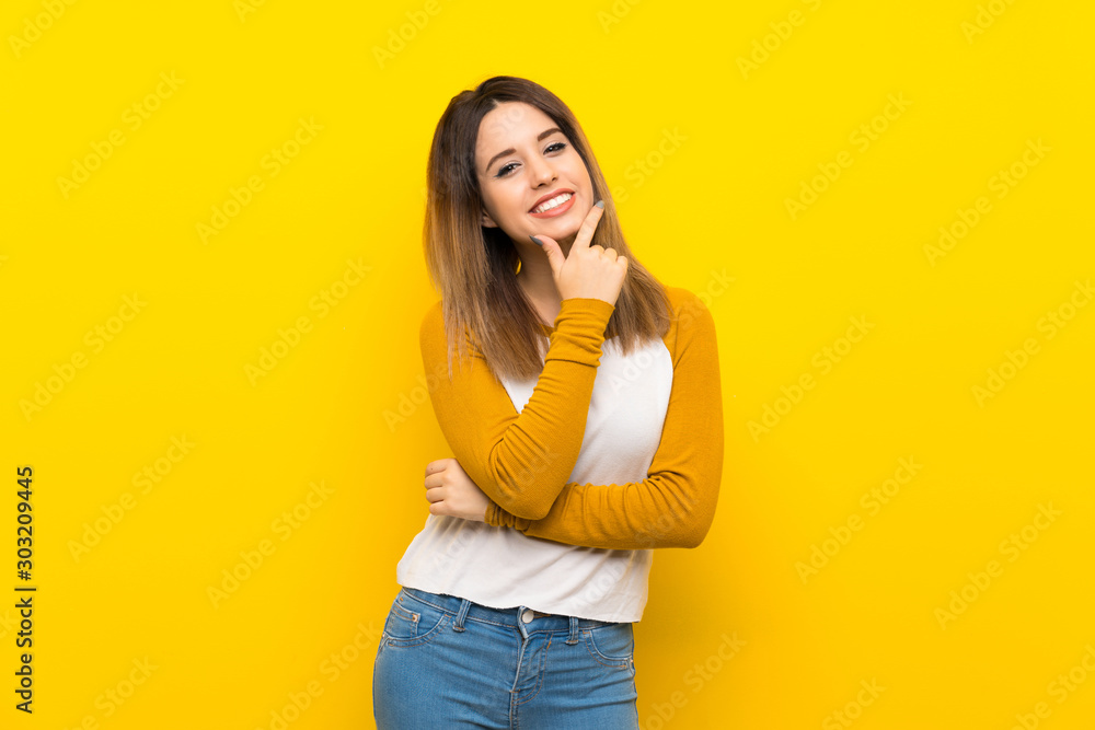 Pretty young woman over isolated yellow wall smiling Pretty young woman over isolated yellow wall smiling