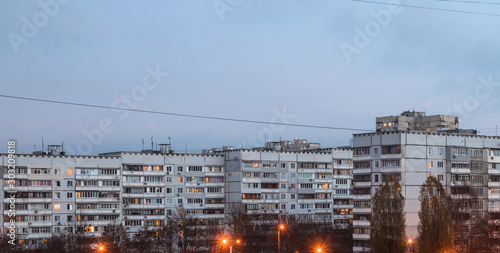 Apartment building at dusk in the light of lanterns, light in the windows, cloudy day, pattern wide photo