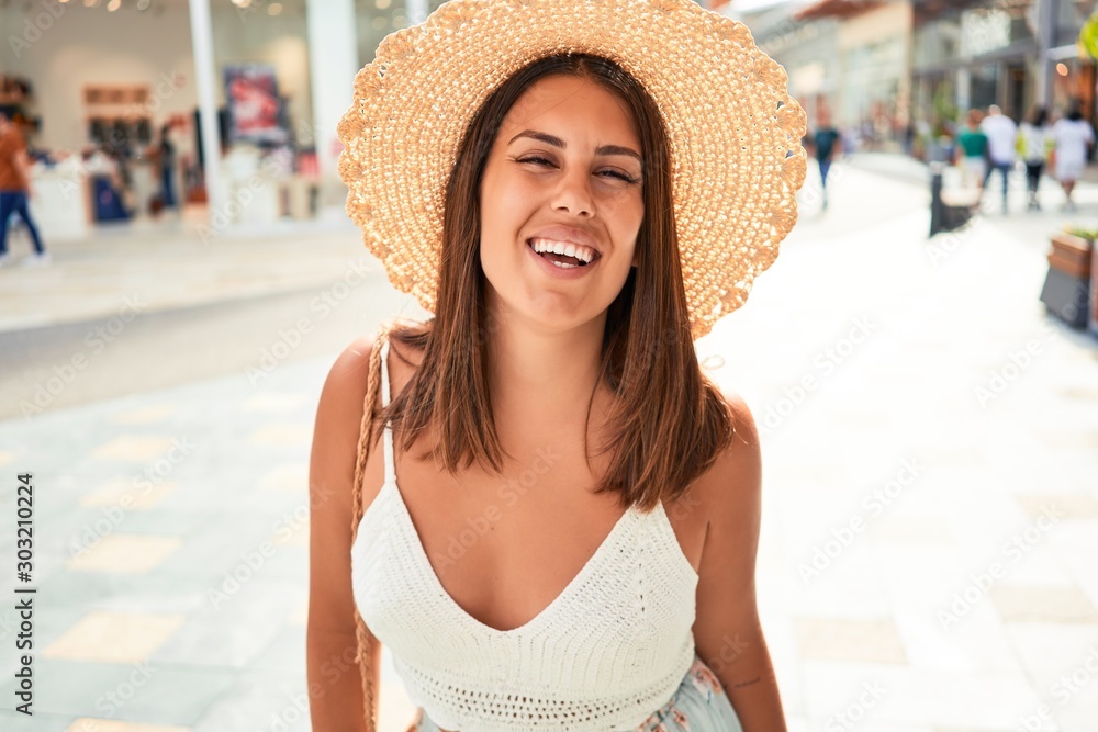 Young beautiful woman inside of shopping center, standing smiling happy and cheerful at the mall on a sunny day of summer