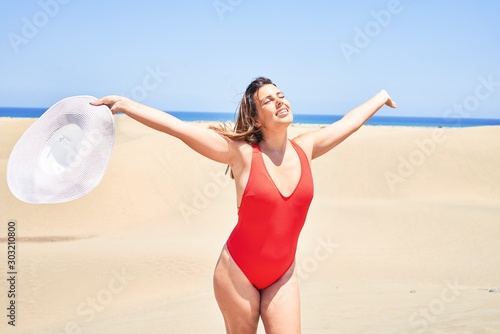 Young beautiful woman sunbathing with open arms wearing summer swinsuit at maspalomas dunes bech photo