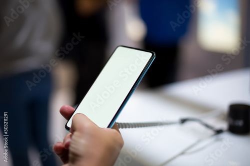  a caucasian man holds new smartphone with white screen copyspace. close up  soft focus. background in blur