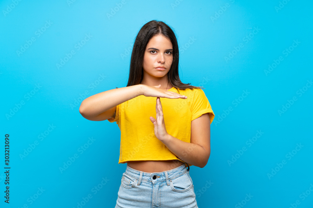 Young girl over isolated blue background making time out gesture Young girl over isolated blue background making time out gesture