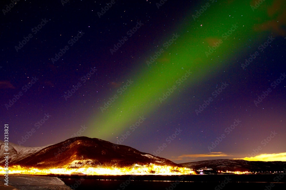 Northern lights above illuminated village in Lofoten peninsula, Norway