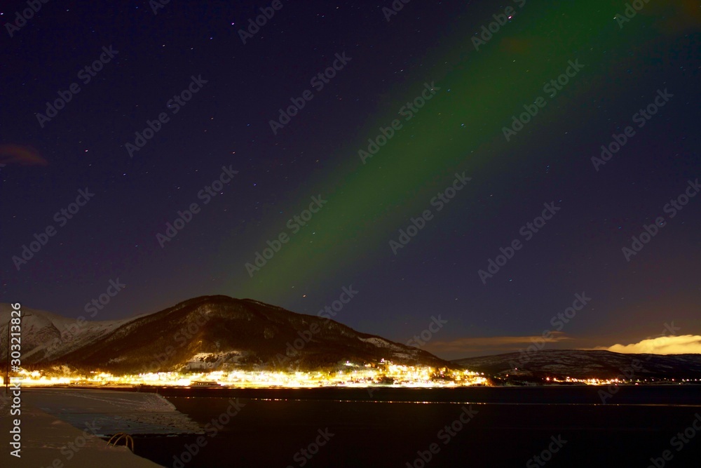 Northern lights above illuminated village, Lofoten, Norway 