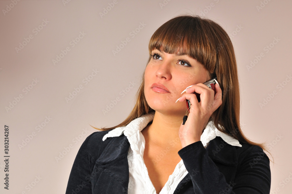 Pretty young caucasian white woman holding near face and talking on mobile phone. Businesswoman life. Female portrait on light background Pretty young caucasian white woman holding near face and talking on mobile phone. Businesswoman life. Female portrait on light background