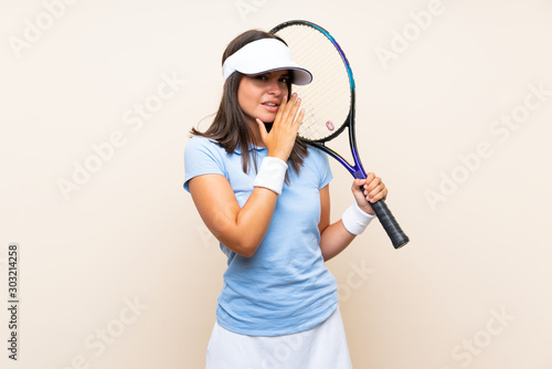 Young woman playing tennis over isolated background whispering something © luismolinero
