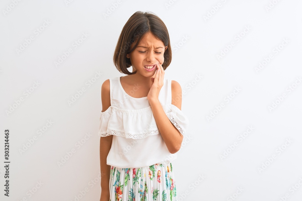 Young beautiful child girl wearing casual dress standing over isolated white background touching mouth with hand with painful expression because of toothache or dental illness on teeth Young beautiful child girl wearing casual dress standing over isolated white background touching mouth with hand with painful expression because of toothache or dental illness on teeth