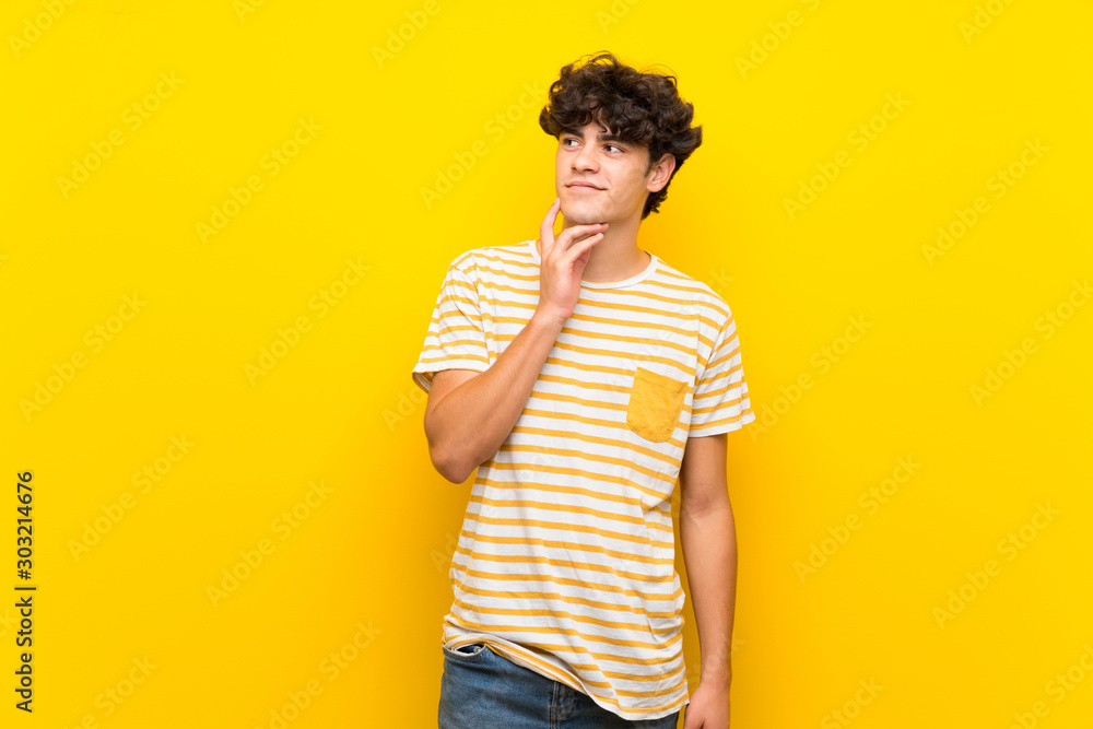 Young man over isolated yellow wall thinking an idea while looking up Young man over isolated yellow wall thinking an idea while looking up