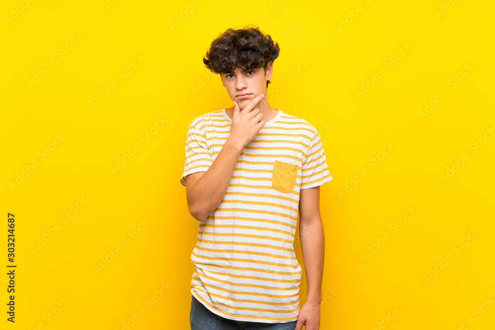 Young man over isolated yellow wall thinking Young man over isolated yellow wall thinking