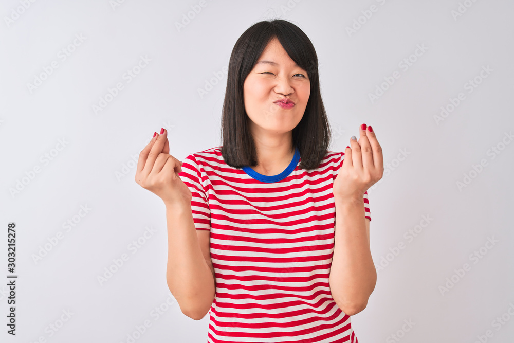 Young beautiful chinese woman wearing red striped t-shirt over isolated white background doing money gesture with hands, asking for salary payment, millionaire business Young beautiful chinese woman wearing red striped t-shirt over isolated white background doing money gesture with hands, asking for salary payment, millionaire business