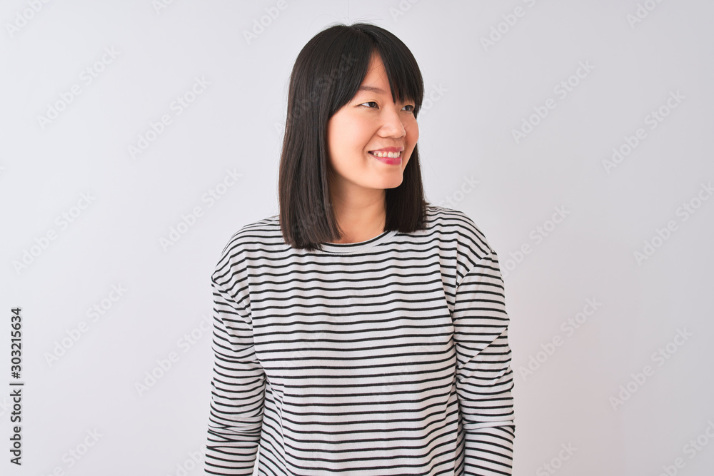 Young beautiful chinese woman wearing black striped t-shirt over isolated white background looking away to side with smile on face, natural expression. Laughing confident. Young beautiful chinese woman wearing black striped t-shirt over isolated white background looking away to side with smile on face, natural expression. Laughing confident.