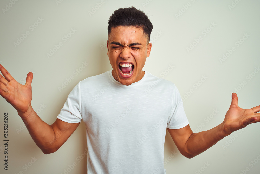 Young brazilian man wearing t-shirt standing over isolated white background celebrating crazy and amazed for success with arms raised and open eyes screaming excited. Winner concept Young brazilian man wearing t-shirt standing over isolated white background celebrating crazy and amazed for success with arms raised and open eyes screaming excited. Winner concept