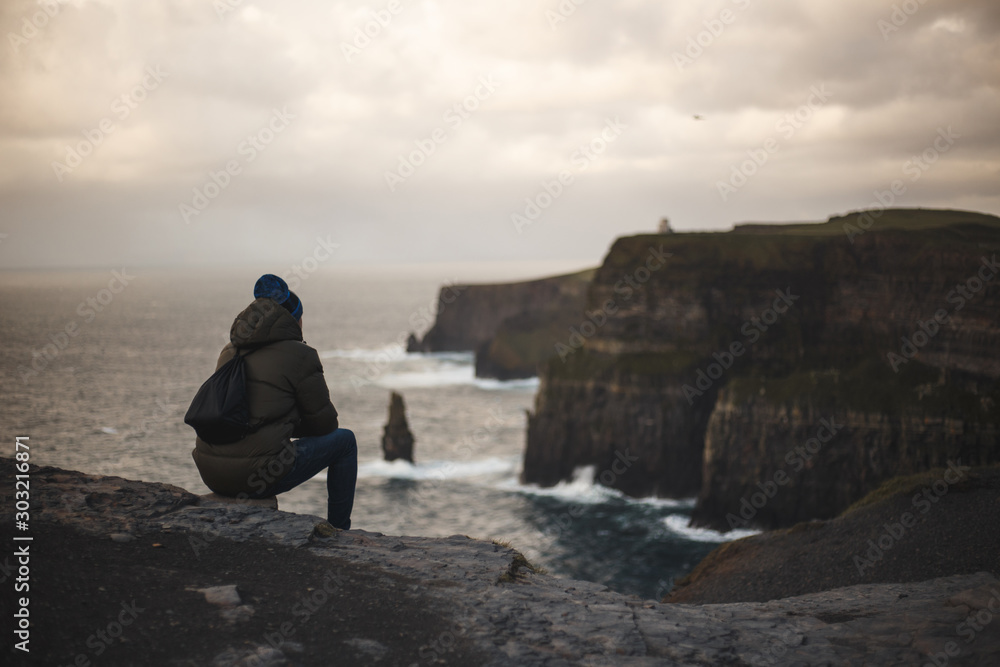Man seated on Cliffs of Moher, Ireland