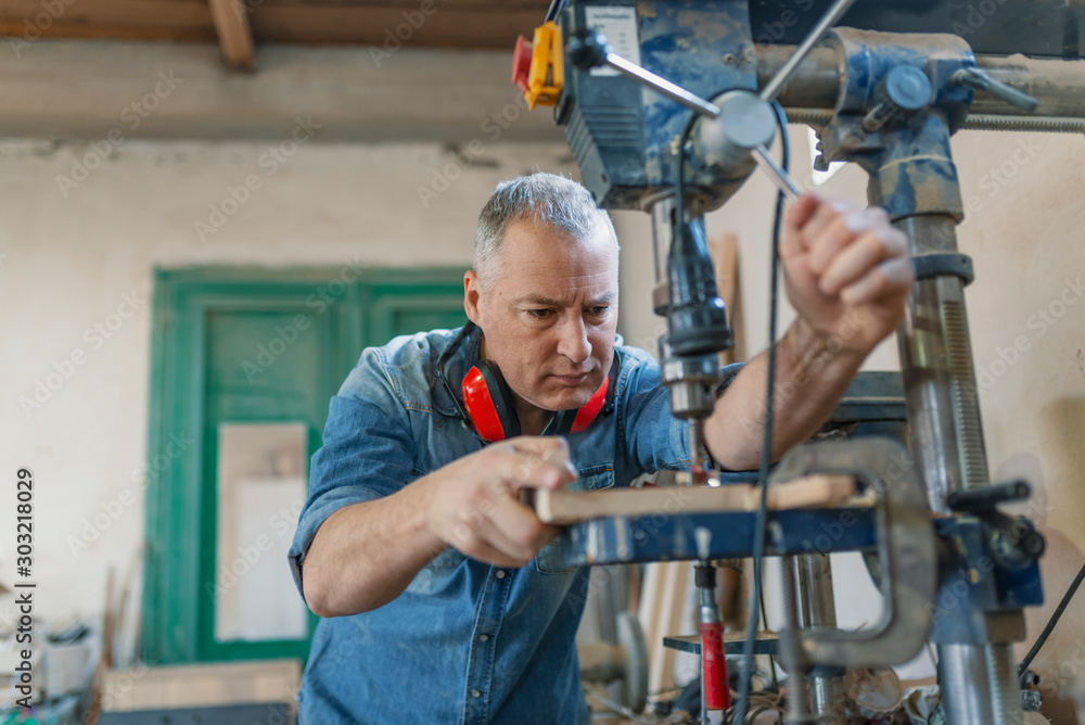 Carpenter working on woodworking machines in carpentry shop. A man works in a carpentry shop.