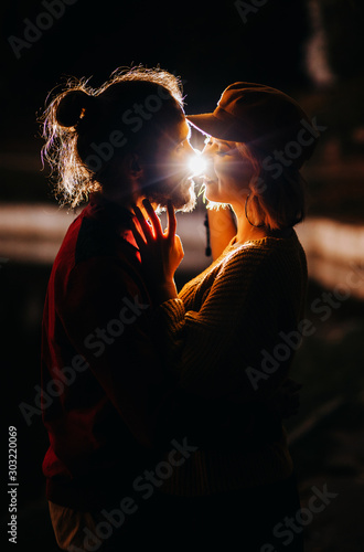 Loving couple looking at each other in the dark. Flashlight illumination. Evening picnic by the lake